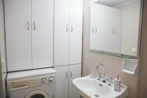Un baño con lavadora, lavamanos y espejo.