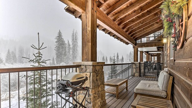 A wooden deck with a grill, a bench, and a view of snow-covered trees. - Four-Season Winter Park Condo w/ Pool Access! (Winter Park)