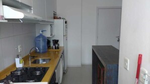 A kitchen with a gas stove, sink, and a large water dispenser. - Apto 2 Quartos na Praia da Cachoeira (Florianópolis)