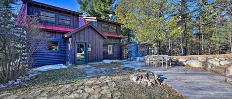 A log cabin with a metal roof, a stone wall, and a wooden deck.