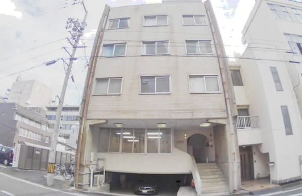 A multi-story building with a central entrance and a covered area at the ground level.