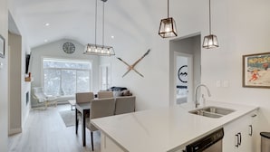 A modern kitchen with a large island, white cabinetry, and pendant lighting. - New 2Bd 2Bth , Ski/Ski Out Condo with Private Hot Tub! (Sun Peaks)