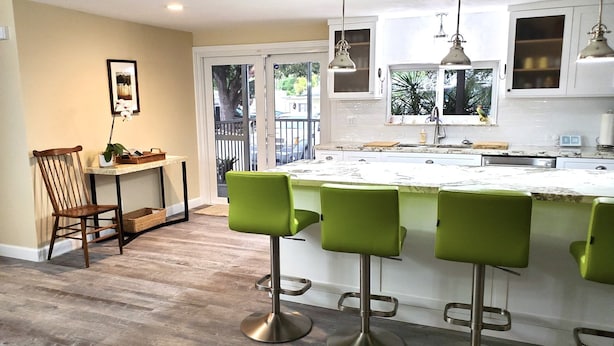 A modern kitchen with a central island, bar stools, pendant lights, and a view to the outside. - Bayside Sunsets (Key Largo)