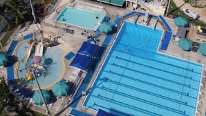 An aerial view of a swimming pool complex with multiple pools, changing rooms, and a covered area with umbrellas. - Bayside Sunsets (Key Largo)