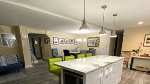 A modern kitchen with a central island, pendant lighting, and a dining area with chairs and a table. - Bayside Sunsets (Key Largo)