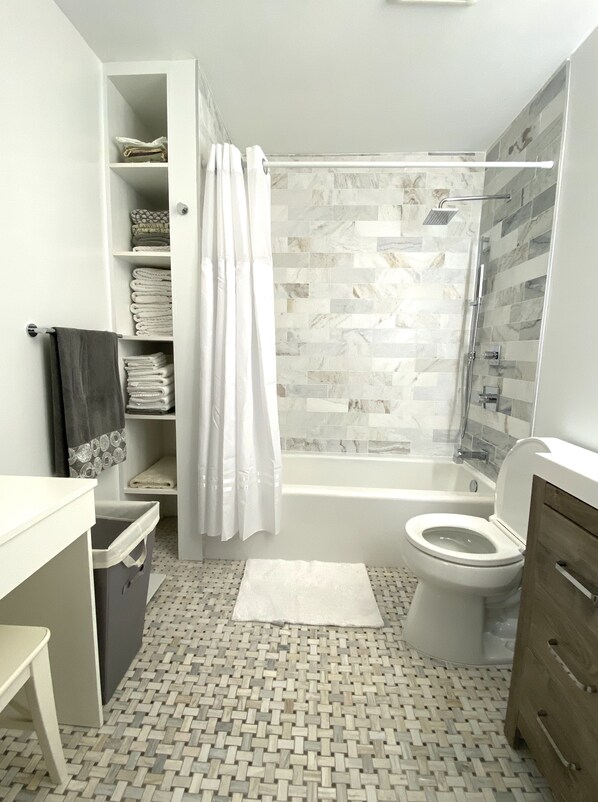 A modern bathroom with a shower, toilet, and storage shelves. - Bayside Sunsets (Key Largo)