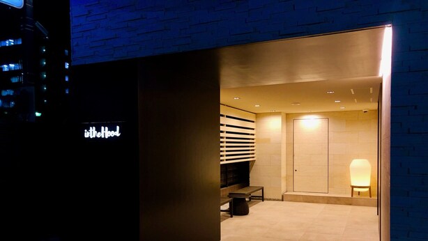 A modern interior with a reception desk, a seating area, and a door leading to a bathroom.