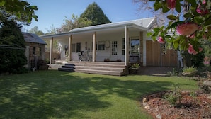 Een gelijkvloers huis met een overdekte veranda, een kleine voortuin en een houten omheining.
