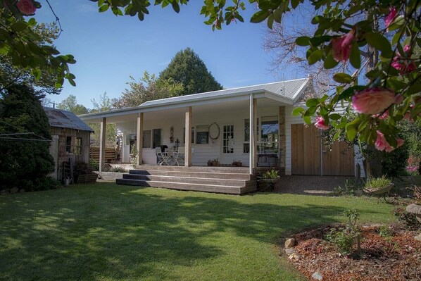 A single-story house with a covered porch, a small front yard, and a wooden fence.