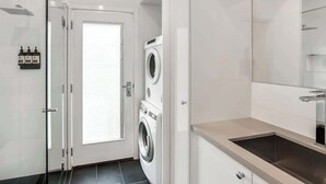 Un baño moderno con cabina de ducha de vidrio, lavadora integrada y lavamanos con espejo.