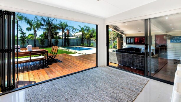 Un interior moderno con un amplio ventanal corredera que da a una zona de piscina exterior.
