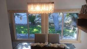A dining area with a table set for four, a chandelier, and a view of a snowy landscape through large windows.