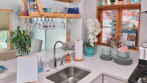 A modern kitchen with a built-in sink, wooden shelves, and a window with a view.