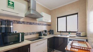 A modern kitchen with a microwave, coffee maker, toaster, and a first aid sign.