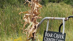 Une enseigne pour le « Bear Creek Country Cabin », avec une tige de maïs et des citrouilles.