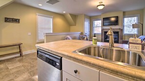 A kitchen with a dishwasher, a stainless steel sink, a bench, and a fireplace with a TV above it. - River Street Roost - 12 Miles to Sun Valley Resort (Hailey)