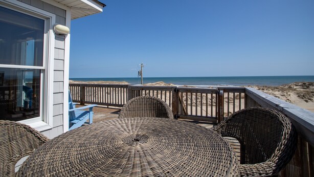 A wooden deck with wicker furniture overlooking a beach. - Lightly Salted OBX, Beach front Luxury, Wild Horses, Pool, Hot Tub, 4x4 Beach (Corolla)