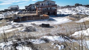 A large, multi-story house with a prominent balcony and a covered outdoor area. - Lightly Salted OBX, Beach front Luxury, Wild Horses, Pool, Hot Tub, 4x4 Beach (Corolla)