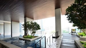 An indoor swimming pool with a wooden ceiling, a view of the city, and a seating area with a chair and a table. - EST Link to LRT KL Sentral Bangsar (Kuala Lumpur)