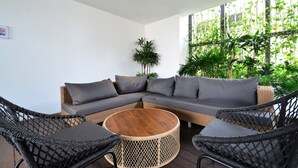 A modern outdoor seating area with a sectional sofa, wicker chairs, and a round wooden table. - EST Link to LRT KL Sentral Bangsar (Kuala Lumpur)