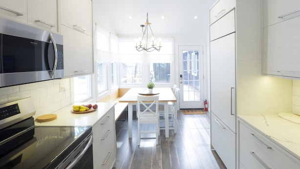 A modern kitchen with white cabinets, a built-in microwave, and a wooden ceiling.