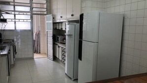 Une cuisine avec des meubles blancs, un four à micro-ondes, un réfrigérateur et une table en bois.