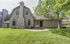 A two-story house with a stone foundation, a chimney, and a covered porch.