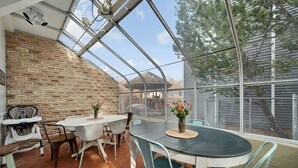 A covered patio with a brick wall, a round table, and chairs. - Unique Home Perfect for Gathering. Pets welcome! (Orem)