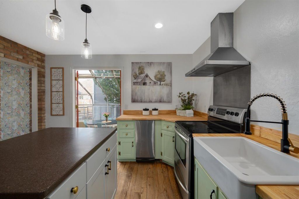 Kitchen with a farmhouse sink, island, and green cabinets