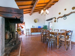 A dining area with a wooden table and chairs, a fireplace, and a chandelier.