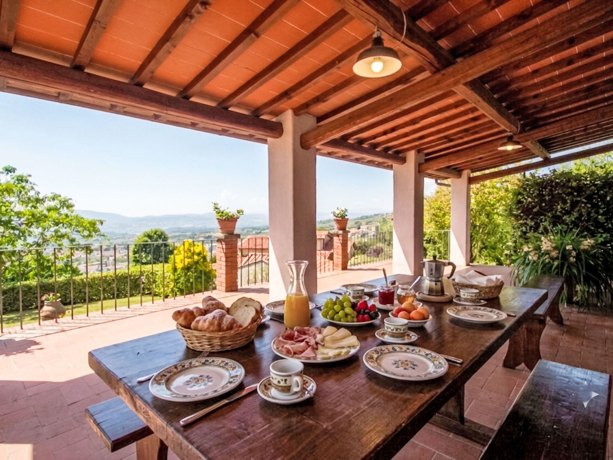 An outdoor dining area with a table set for breakfast, overlooking a scenic landscape.