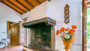 Un interior rústico con chimenea, una puerta de madera y un jarrón de flores.