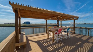 Una terraza de madera con pérgola, una mesa y sillas.