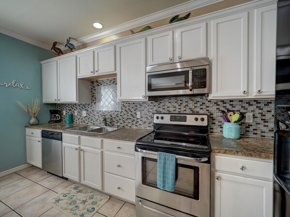 A kitchen with white cabinets, a stainless steel microwave, and a stove.