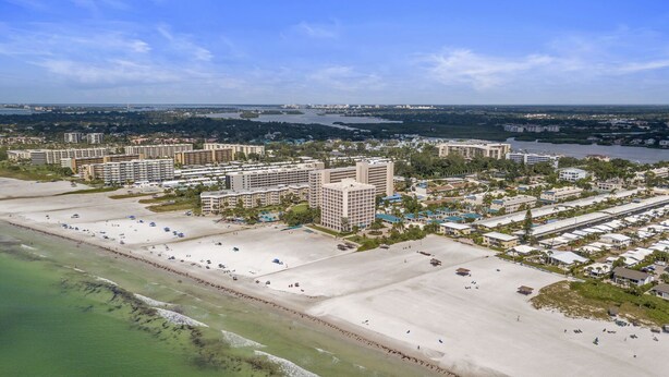 A coastal hotel area with multiple high-rise buildings, a sandy beach, and a marina. - Siesta Beach Condo Rental with direct beach and pool access (Siesta Key)