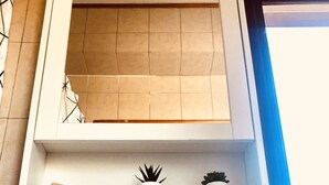 A bathroom with a white sink, a modern faucet, and a shelf above the sink holding a potted plant and a soap dispenser. - Residenza Donna Maria (Ercolano)