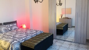 A bedroom with a bed, bedside lamps, a mirror, and a wardrobe. - Residenza Donna Maria (Ercolano)
