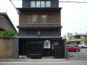 A two-story building with a dark facade, a traditional Japanese lantern, and a sign indicating it is a hotel. - lili kyoto (Kyoto)