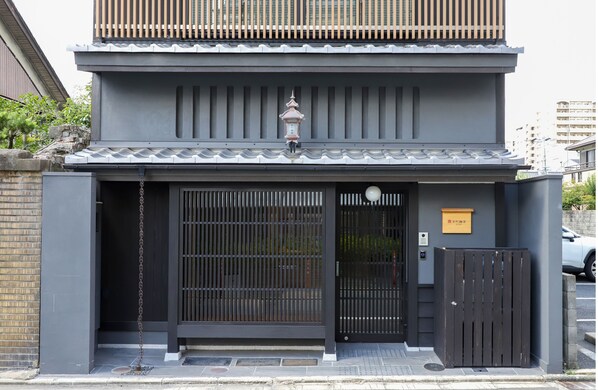 A traditional Japanese building with a dark entrance gate, a small lantern, and a plaque. - lili kyoto (Kyoto)