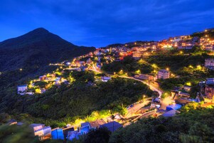 Un pueblo en la ladera de una colina iluminado de noche, con calles serpenteantes.