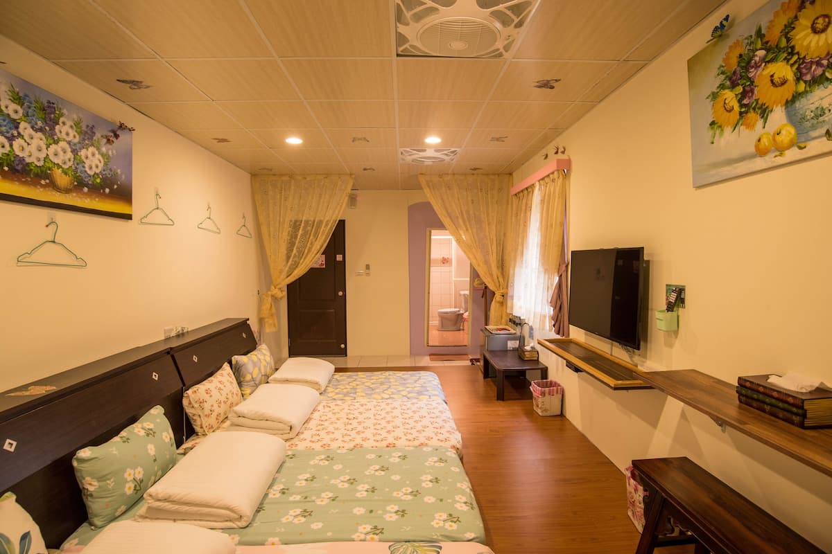 A hotel room with two beds, a TV, a desk, and a bathroom visible through an open door.