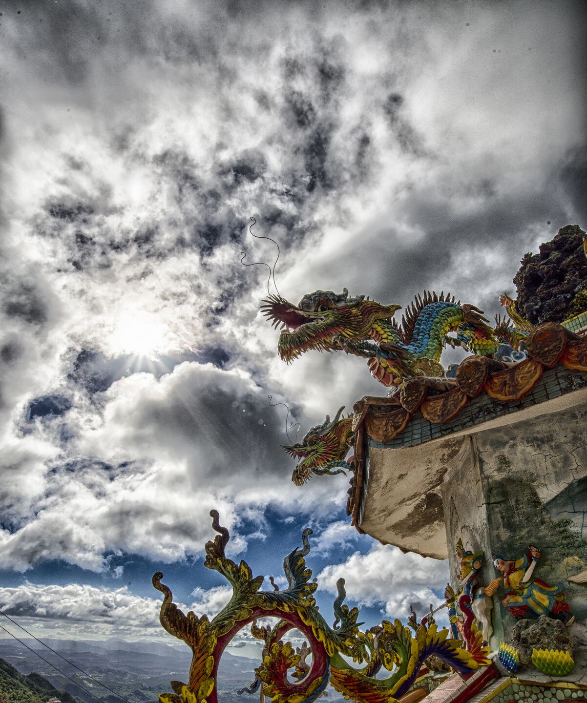 A dragon sculpture on a building's edge with a cloudy sky in the background.