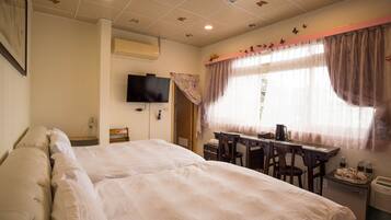 A hotel room with two beds, a desk, a chair, a television, and a window with curtains.