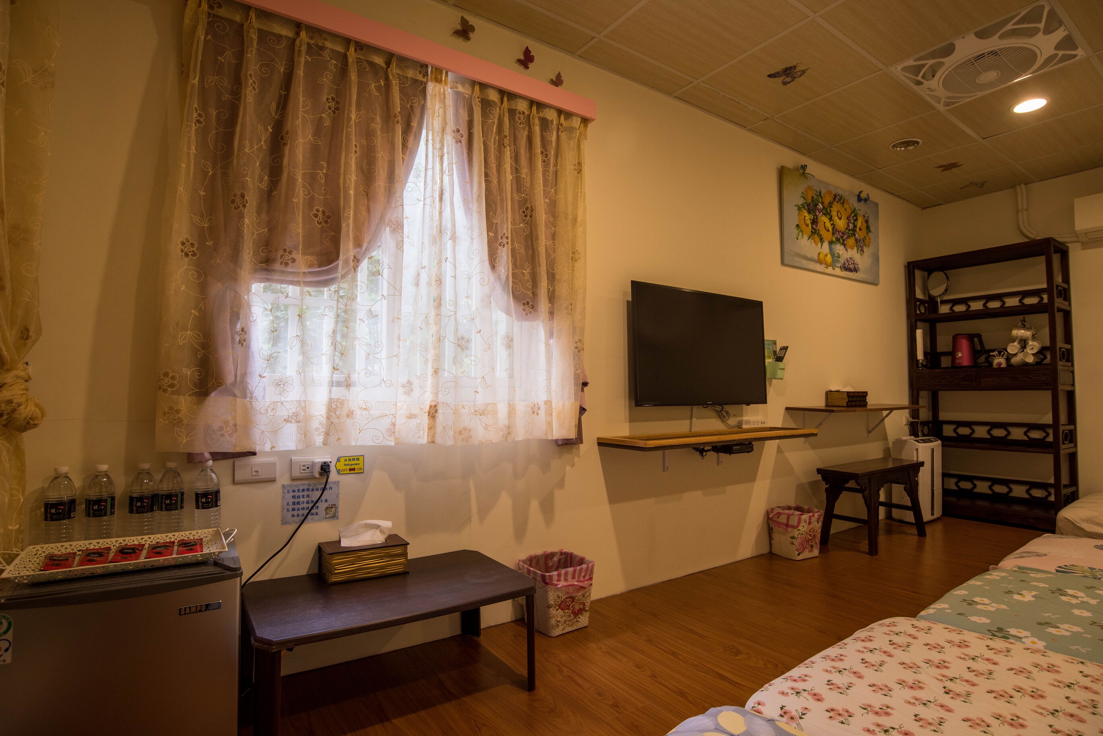 A room with a bed, a desk with a computer, a TV, and a small refrigerator.