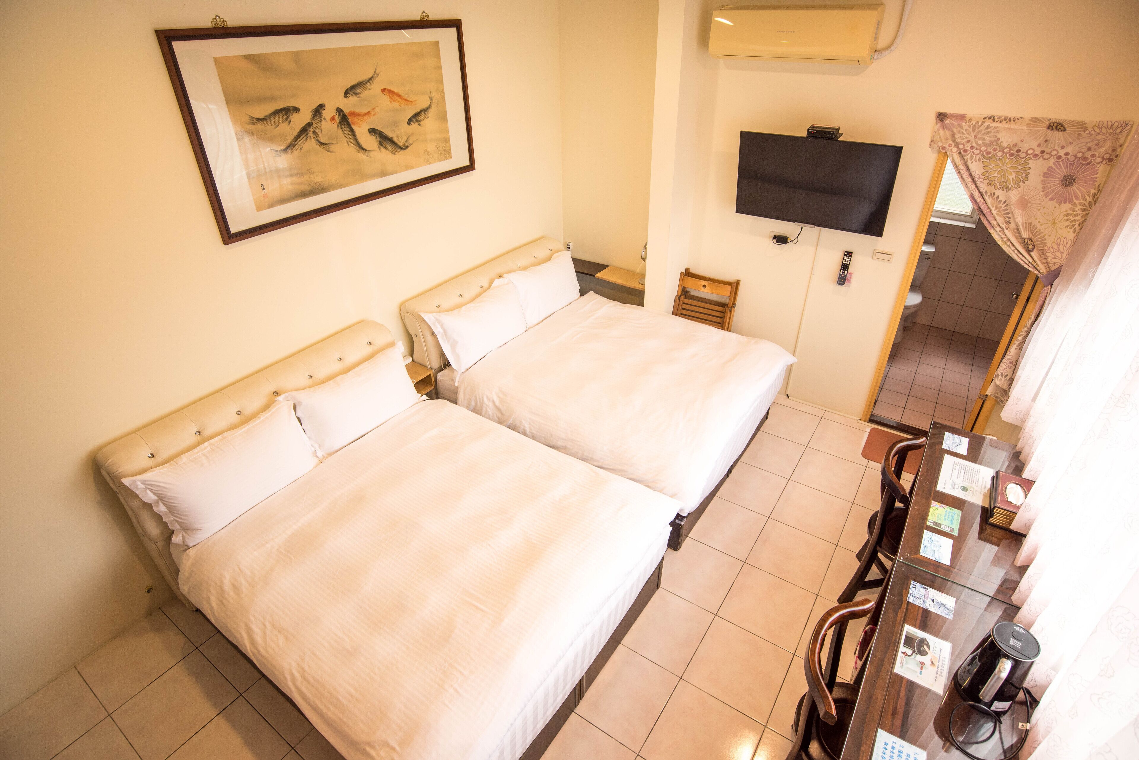 A hotel room with two beds, a television, a coffee machine, and a painting on the wall.