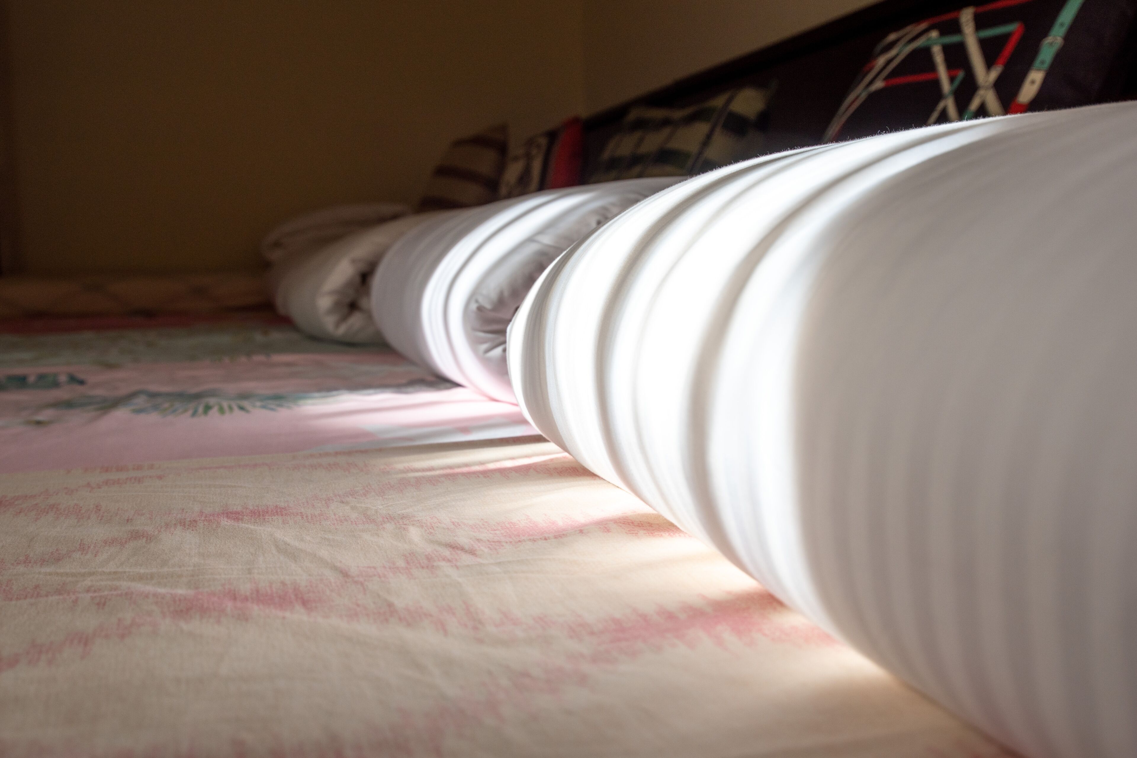 Una cama con ropa de cama blanca y una colcha estampada.