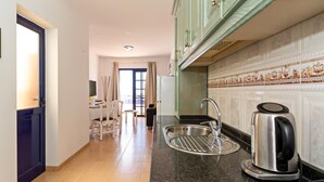 A modern kitchen with a stainless steel sink, a kettle, and a dining area with chairs and a table. - Apartment Tropical Center Playa Blanca By PVL (playa blanca)