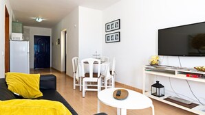 A modern living room with a sofa, a dining table, and a TV. - Apartment Tropical Center Playa Blanca By PVL (playa blanca)