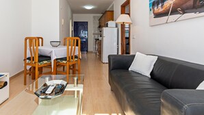 Ein gemütlicher Wohnbereich mit Essplatz, einer Couch, einem Glastisch und einer Küche im Hintergrund.