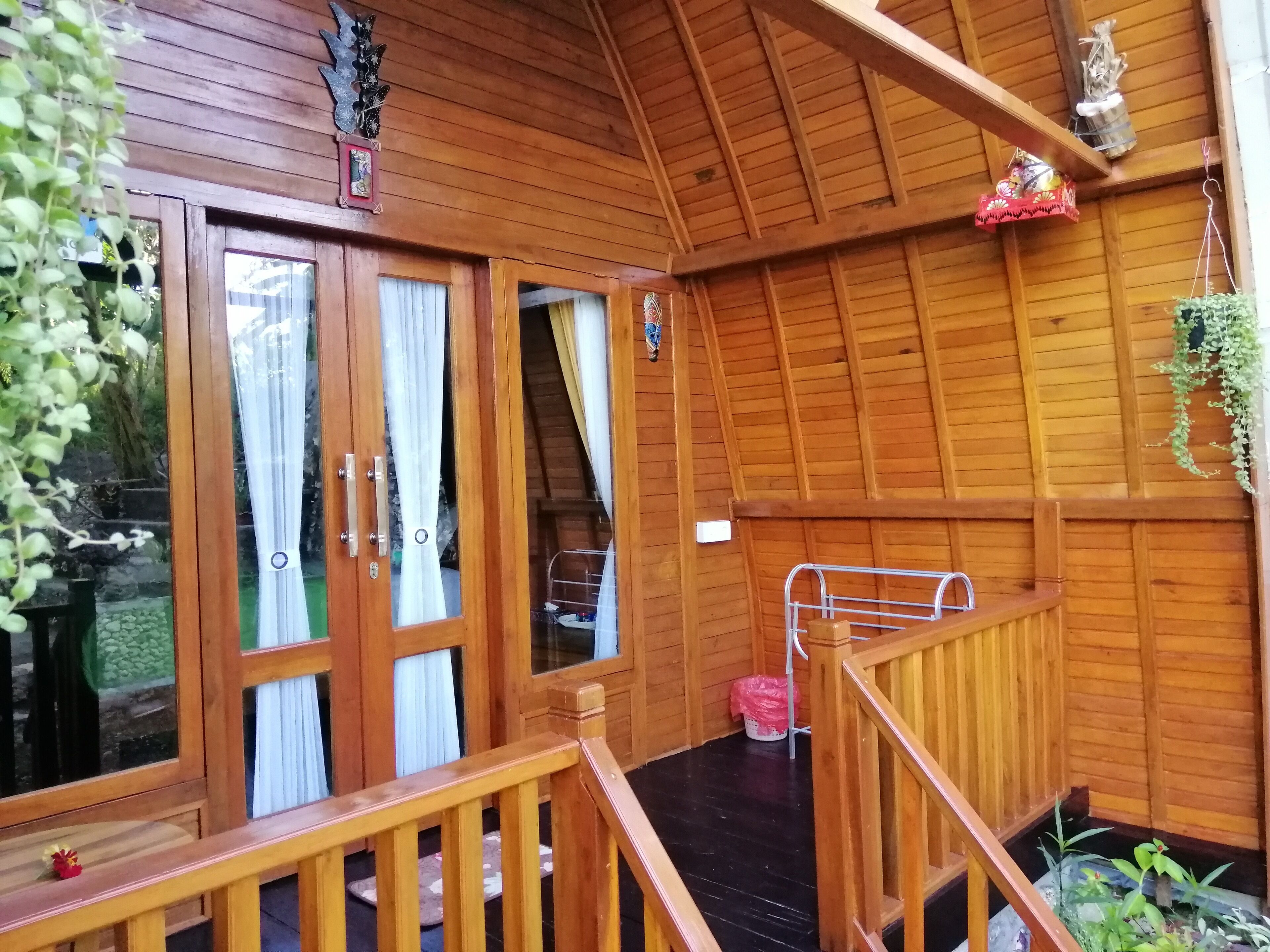 A wooden cabin with a balcony, wooden railings, and a small garden area.